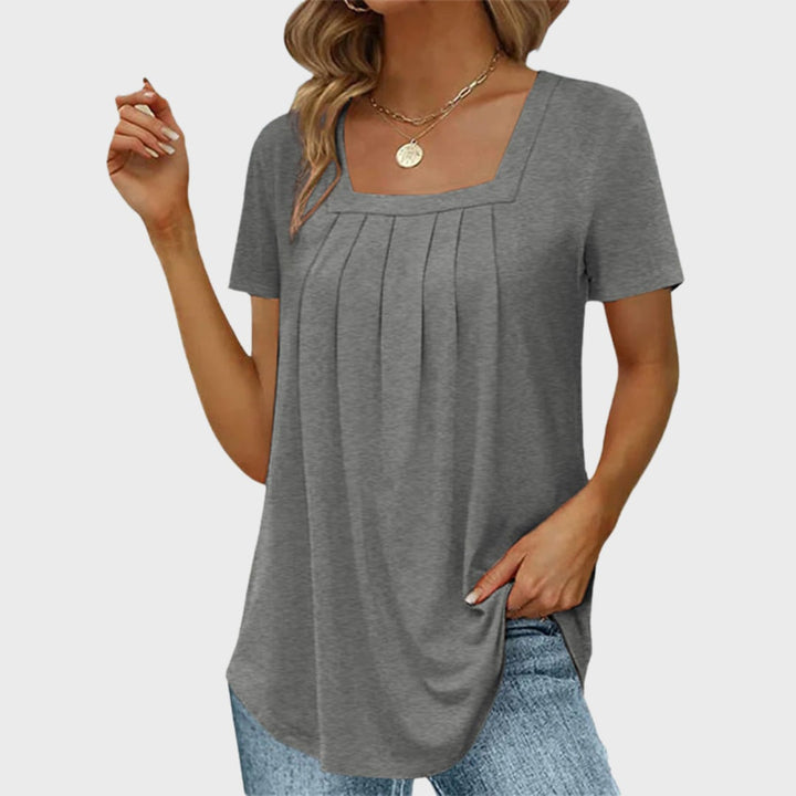 Flat lay of a lightweight square-neck blouse in pink showing fabric texture and pleat detail