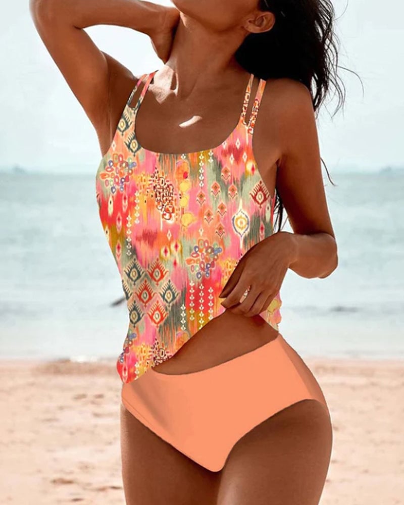 Woman wearing a colorful boho print tankini with high-waisted bottoms, standing poolside in bright summer light