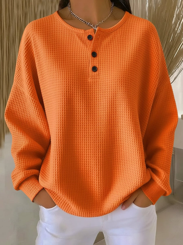 Woman wearing a relaxed-fit casual sweatshirt in orange, paired with casual pants for an easy everyday look