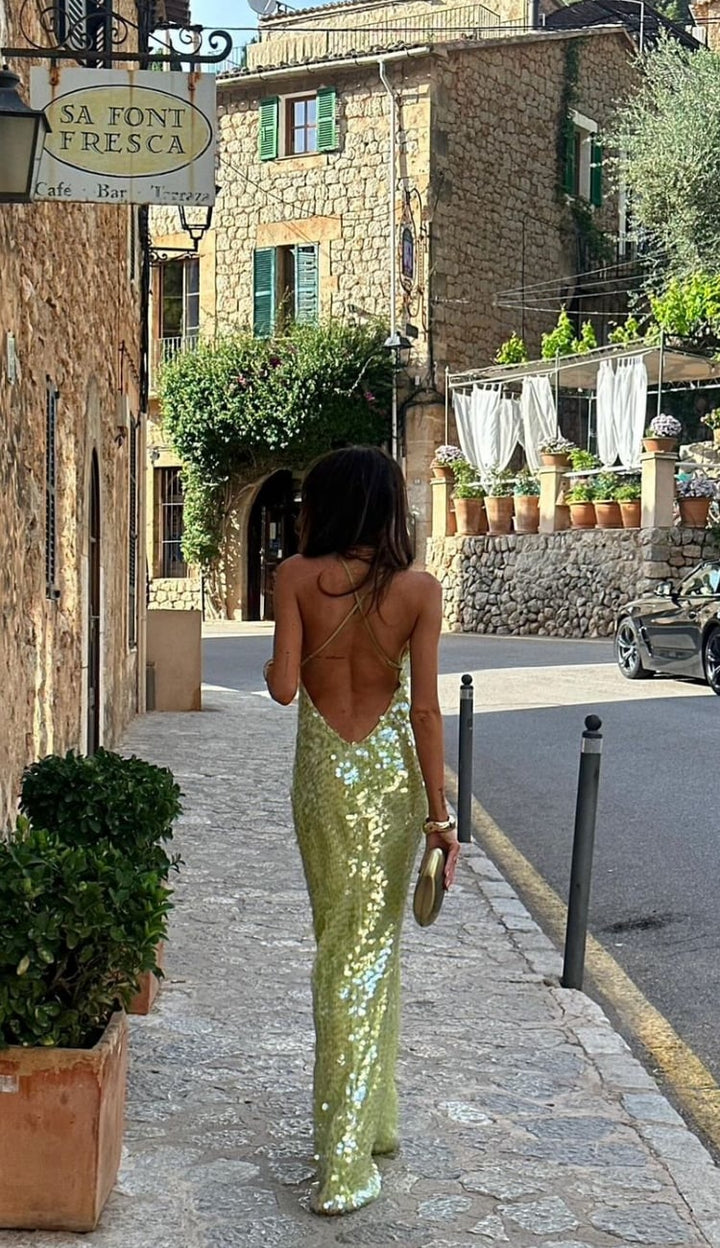 Full-length side view of a woman in the green sequin backless Odette dress