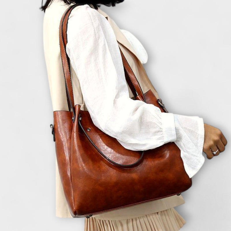 Model carrying the Olivia shoulder bag in brown over her shoulder in an outdoor setting