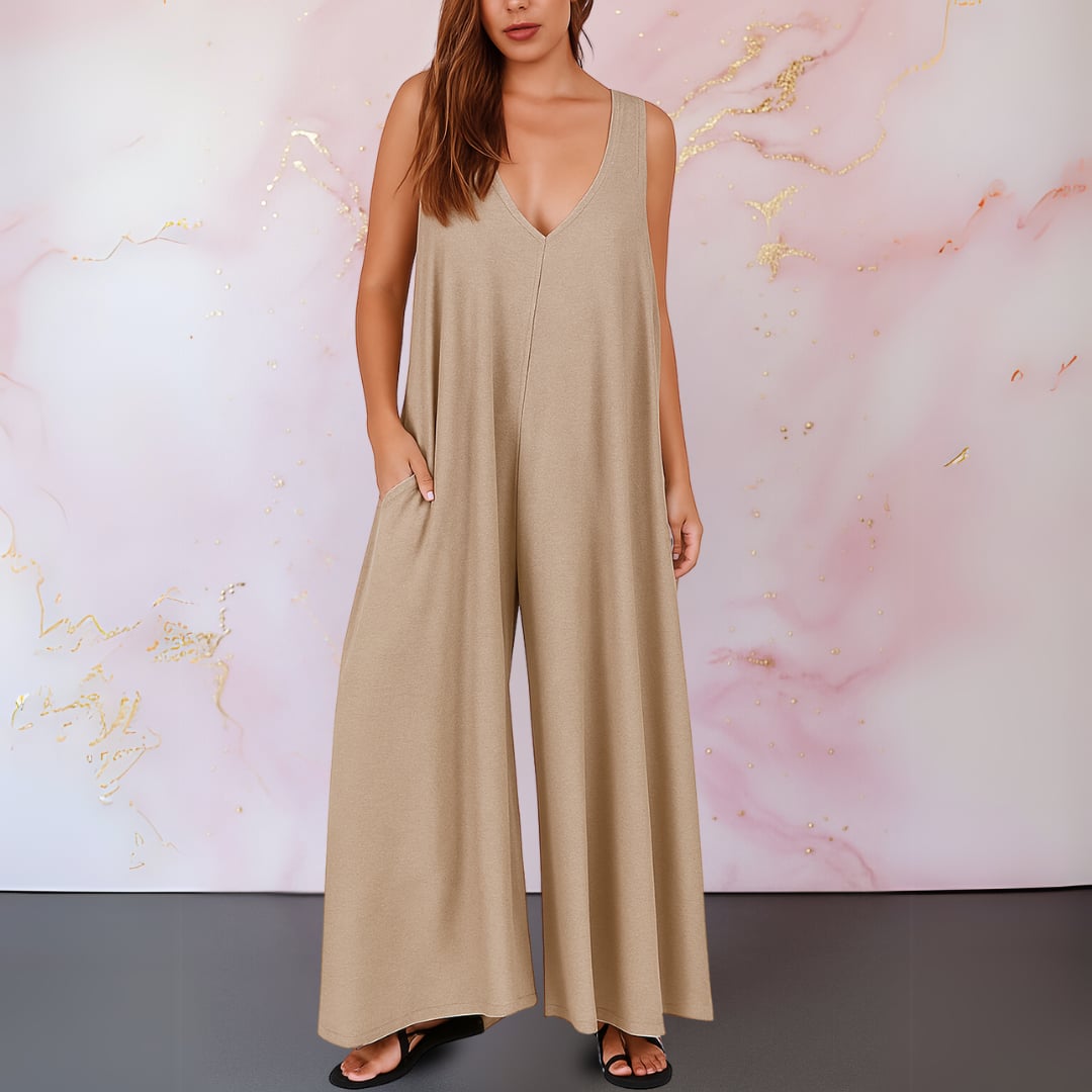 Woman wearing a gray wide-leg sleeveless jumpsuit styled with strappy sandals