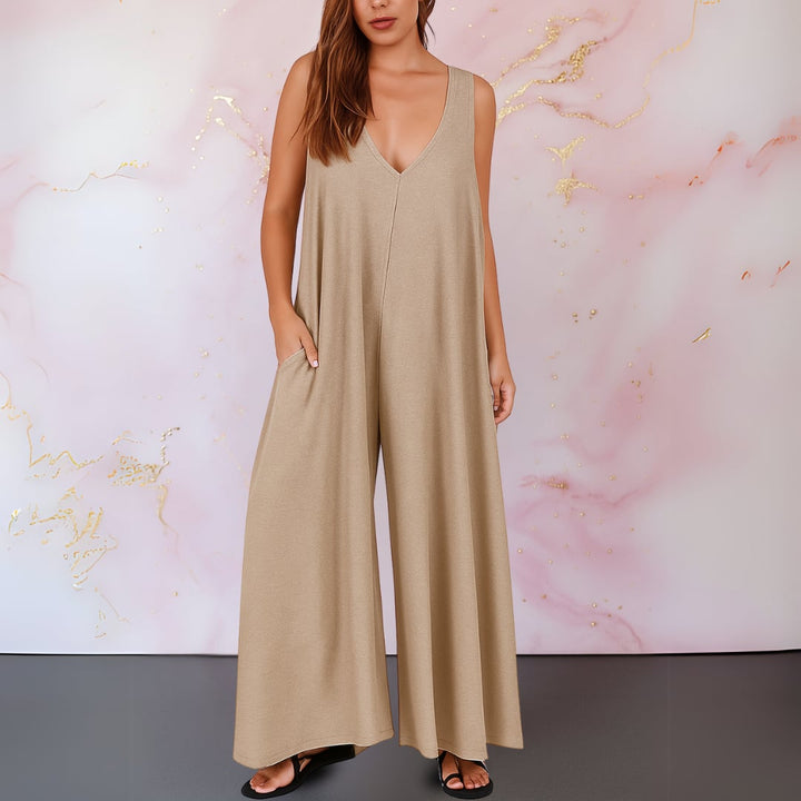 Woman wearing a gray wide-leg sleeveless jumpsuit styled with strappy sandals