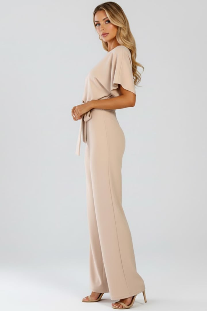 Woman in black wide leg short sleeve jumpsuit with tie belt, full length front view