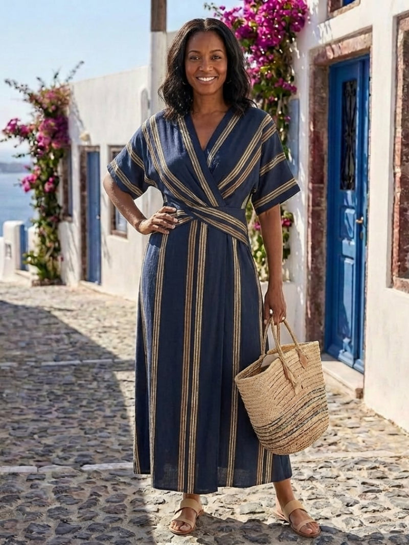 Side view of a woman in the navy striped wrap maxi dress highlighting the flowing maxi length and silhouette