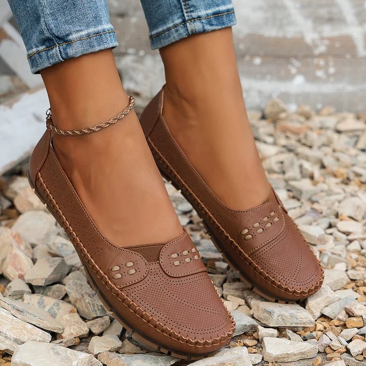 Pair of Paulette orthopedic flats in brown arranged on a light surface, top-down view