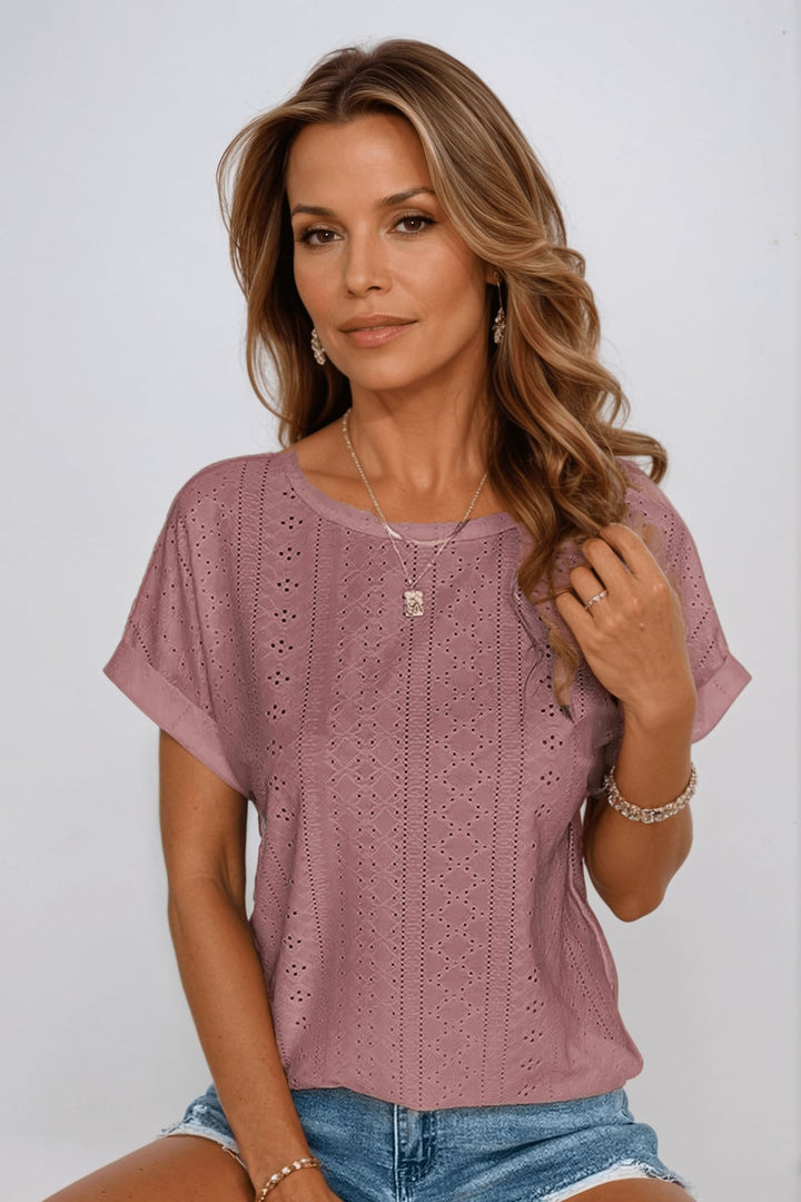 Woman styling the eyelet embroidered top tucked into high-waisted bottoms, side view