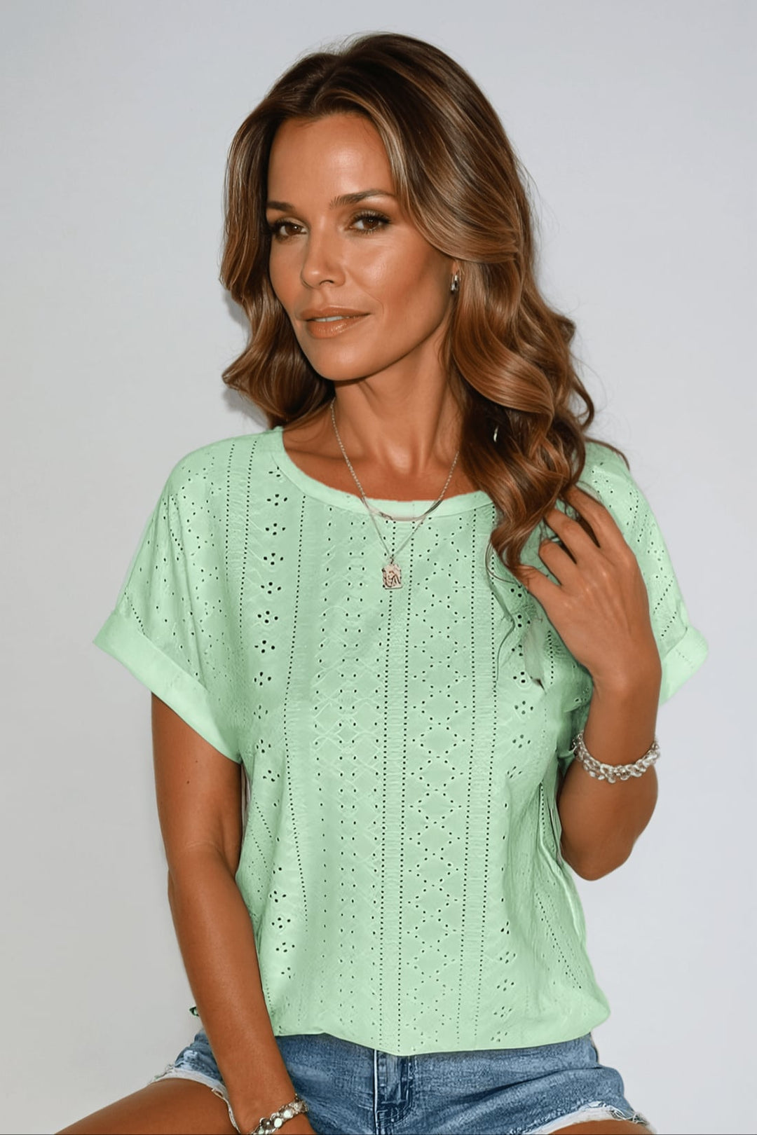 Flat lay of the eyelet embroidered top in multiple color options including white, black, and purple