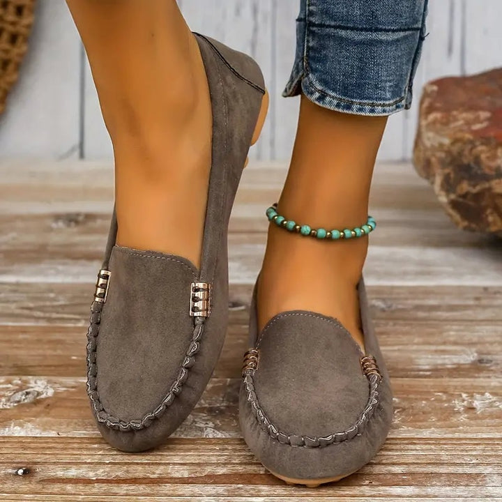 Side view of Penny women's moc-toe loafer in gray showing suede-look texture and gold accent bar detail