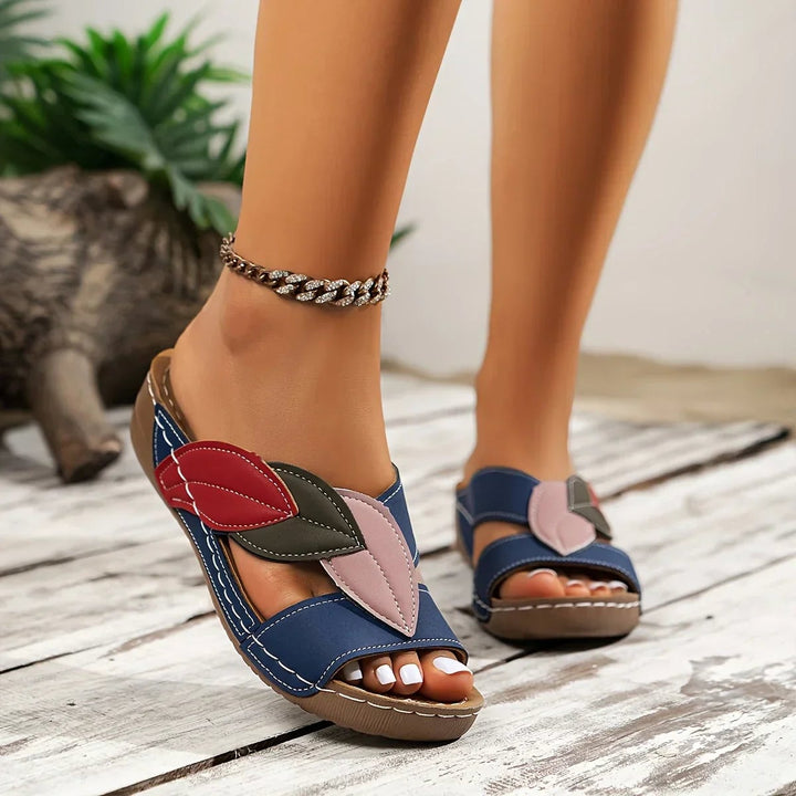 Overhead flat-lay of all four Petal sandal color options: white, black, pink, and blue