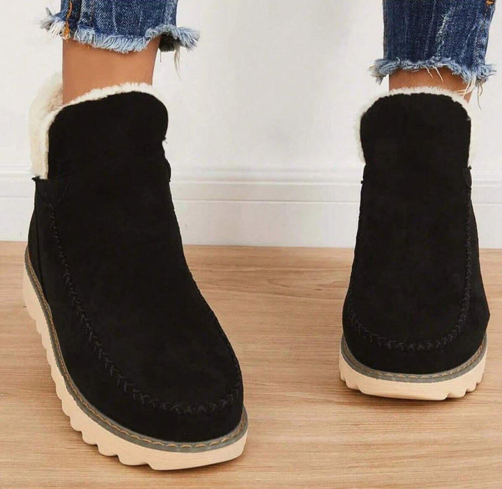 PolarBelle winter boots in brown styled with dark skinny jeans on a snowy background