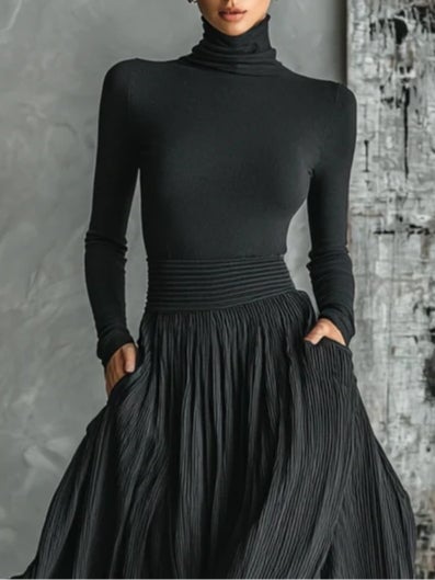 Model wearing black turtleneck and pleated maxi skirt coordinated set, full-length front view
