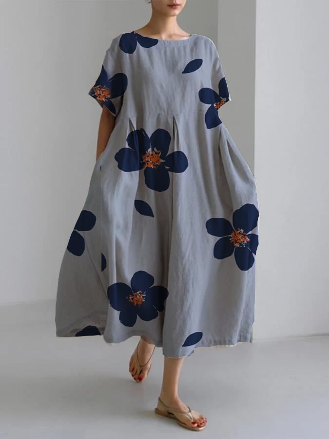 Woman wearing the Raffaella long floral maxi dress in blue with a relaxed fit, featuring deep blue flowers with orange centers on a neutral background