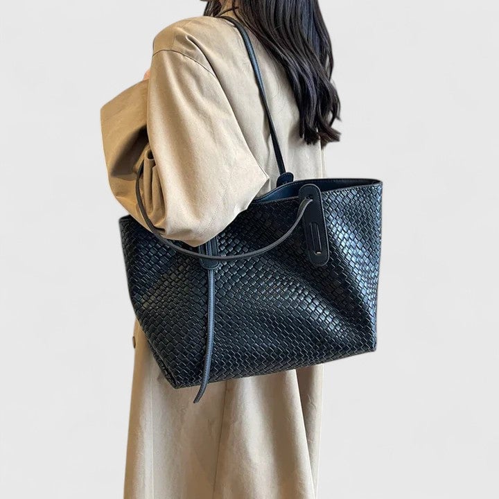 Black woven tote bag carried over the shoulder on a model