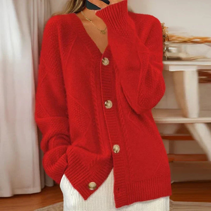 Reagan cable knit cardigan in pink, draped over the shoulders for a cozy layered look