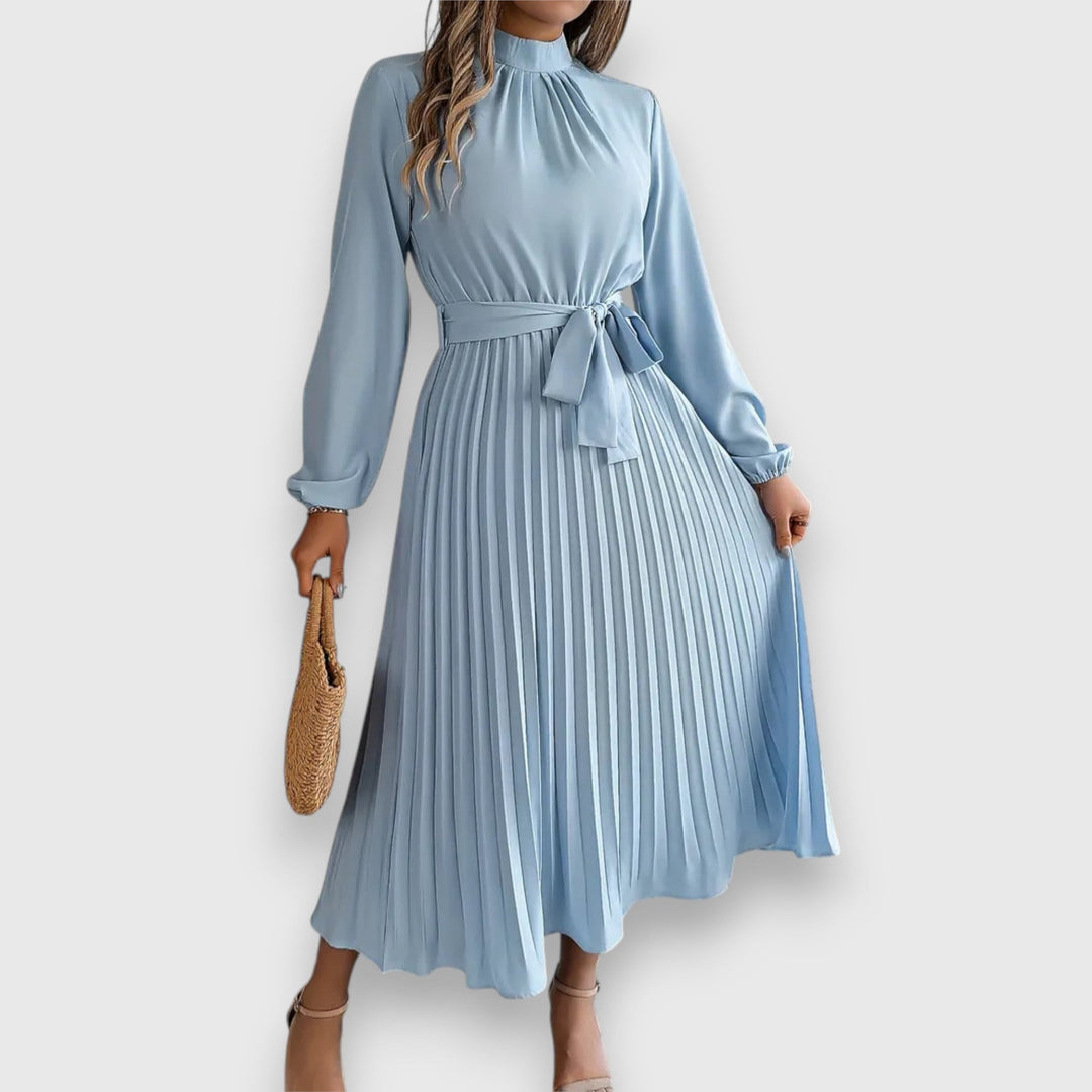 Model wearing an elegant pleated midi dress in light blue with flowing skirt detail