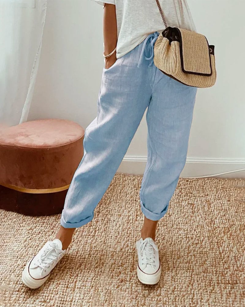 Full-length view of straight-leg trousers in a neutral solid color, styled with a tucked-in blouse