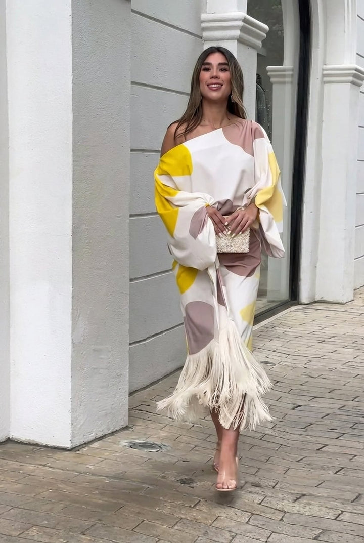 Woman wearing the Rhiannon one shoulder fringe midi set in Beige, featuring asymmetric neckline and flowing fringe detailing