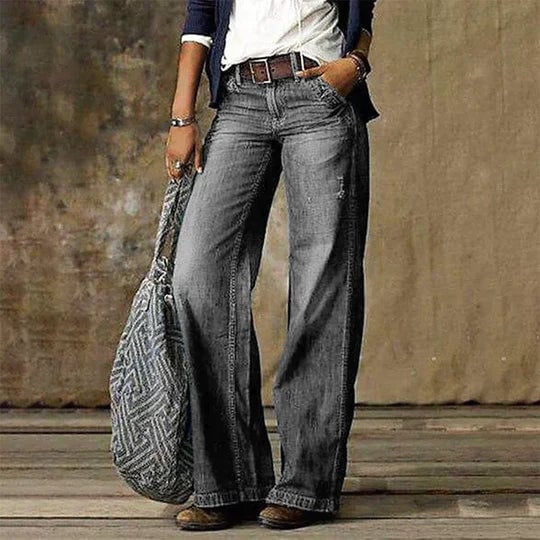Woman styling River flare jeans with a tucked-in blouse and ankle boots, side view