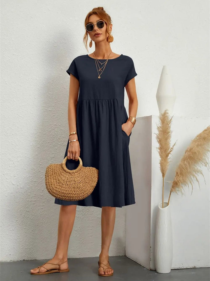 Model wearing casual pocket dress in a solid color, paired with sandals for a polished yet relaxed outfit