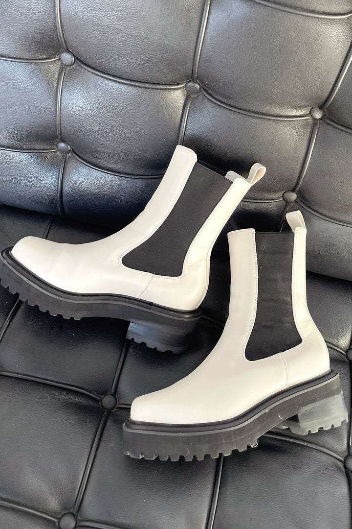 Close-up detail of women's white two-tone ankle boots highlighting the bold contrast finish and cushioned structure