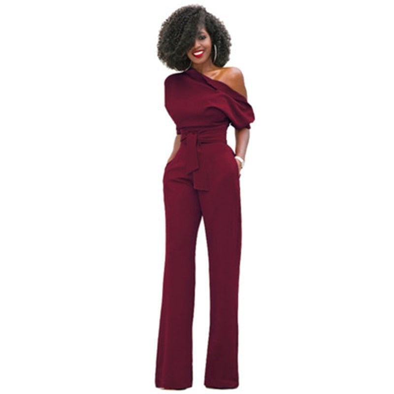 Full-length lifestyle shot of a woman in the Rosa belted wide-leg jumpsuit styled with strappy heels