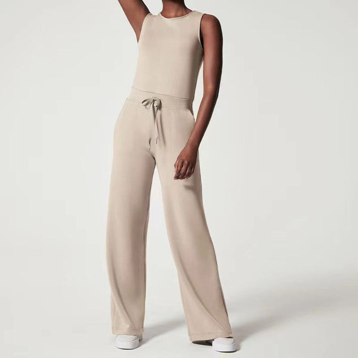 Woman wearing a beige sleeveless wide-leg jumpsuit with an adjustable waist tie, styled for a casual daytime look