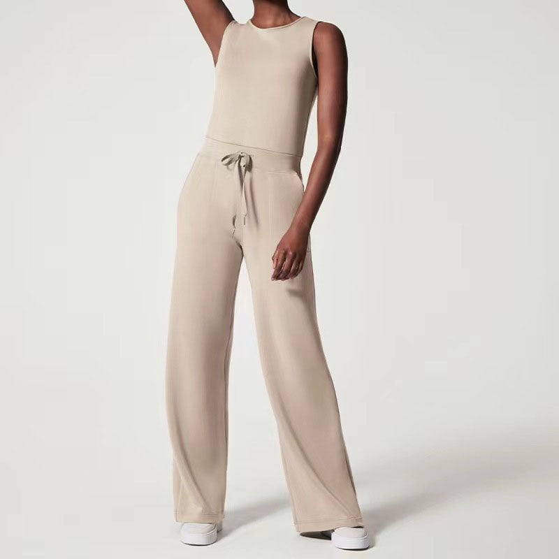 Woman wearing a beige sleeveless wide-leg jumpsuit with an adjustable waist tie, styled for a casual daytime look