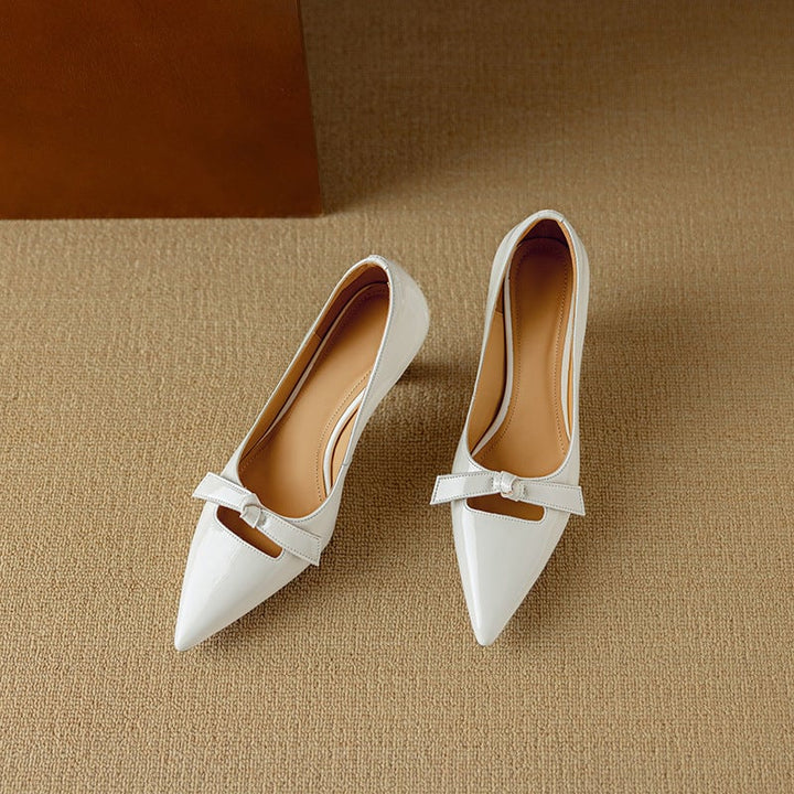 Pair of Rosalind white bow pumps on flat surface, angled view