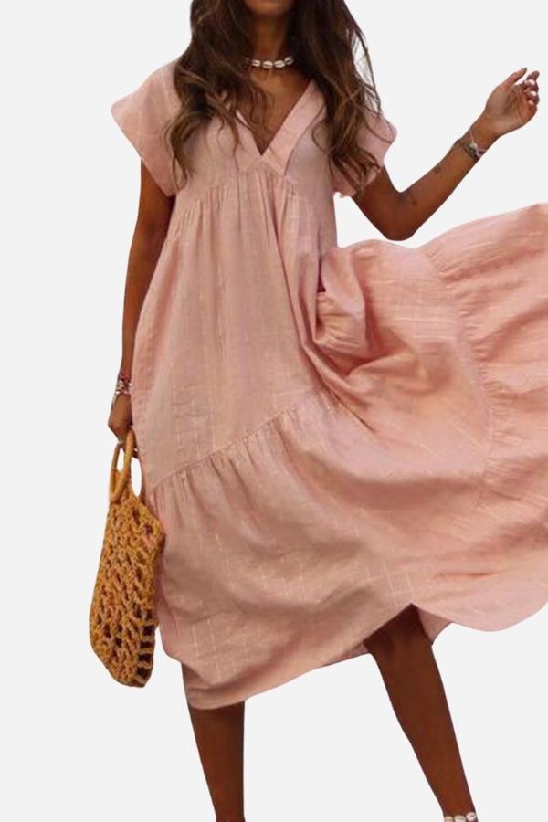 Woman wearing the Rosie V-neck tiered midi dress with flutter sleeves in peach fuzz, flowing skirt at midi length
