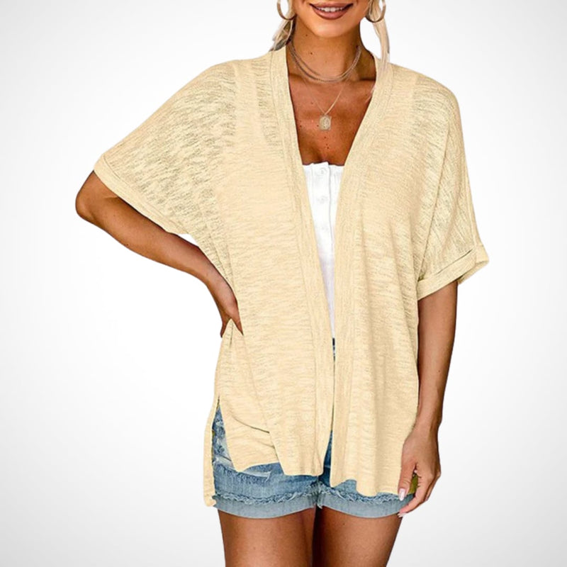 Woman wearing a flowy short sleeve open-front cardigan in apricot, styled over a white top