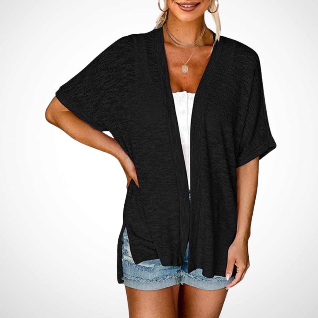 Woman in a flowy short sleeve cardigan in white, paired with light-wash jeans outdoors