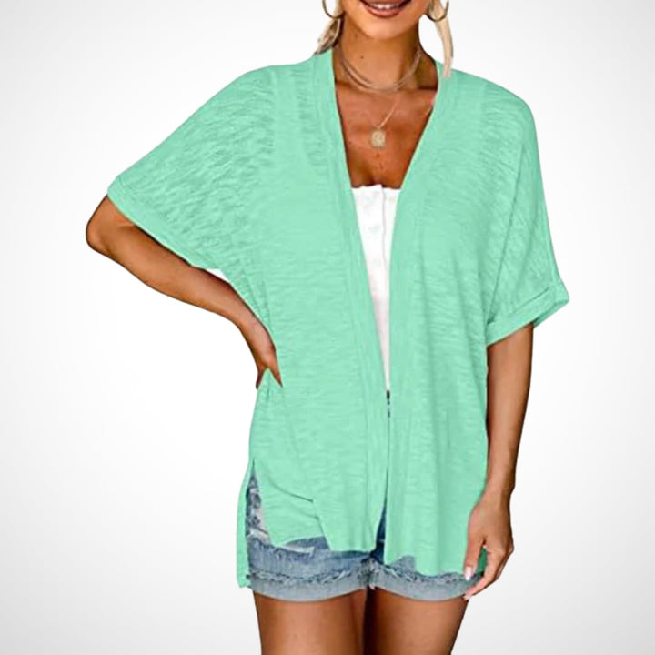 Woman wearing a jade green flowy cardigan over a sundress in a bright outdoor setting