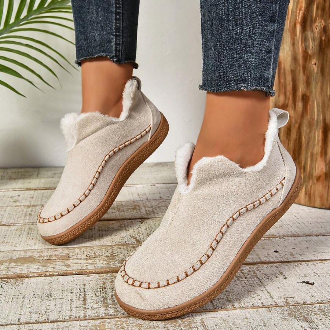 Beige slip-on ankle boots with plush fur lining and thick outsole, quarter view