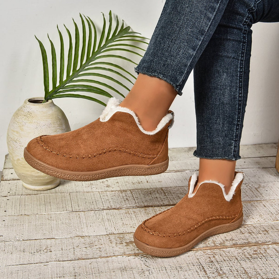 Pair of grey fur-lined slip-on ankle boots laid flat on neutral background