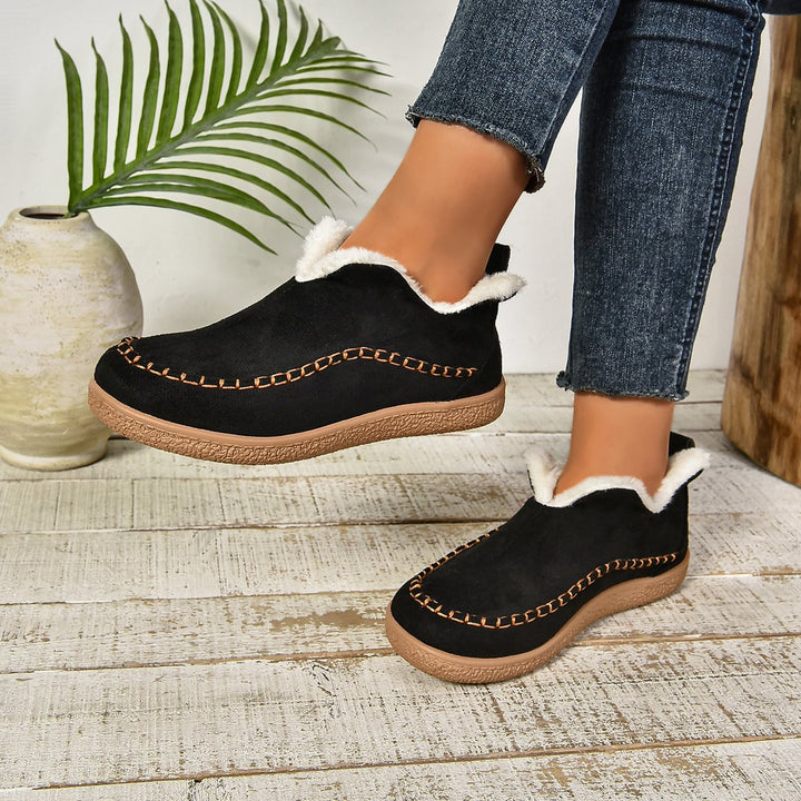 Back view of black fur-lined slip-on ankle boots showing heel and sole detail