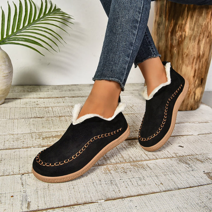 Brown warm slip-on ankle boots on a winter pavement surface