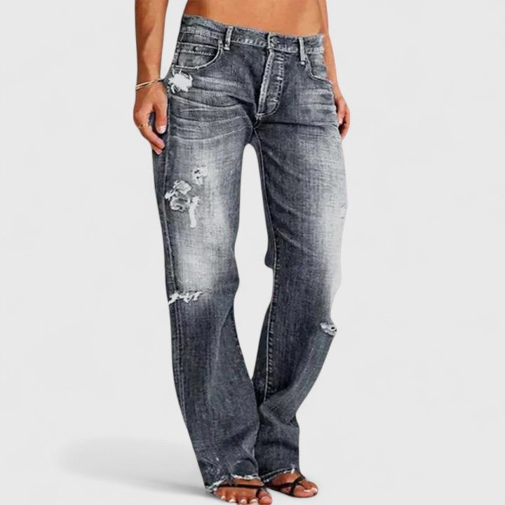 Model wearing Sadie low-rise jeans in dark blue paired with a white cropped top and sneakers