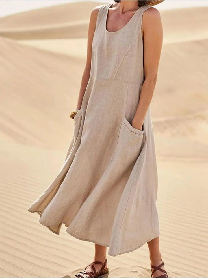Woman wearing a flowy sleeveless linen maxi dress with scoop neckline and side pockets in sage green