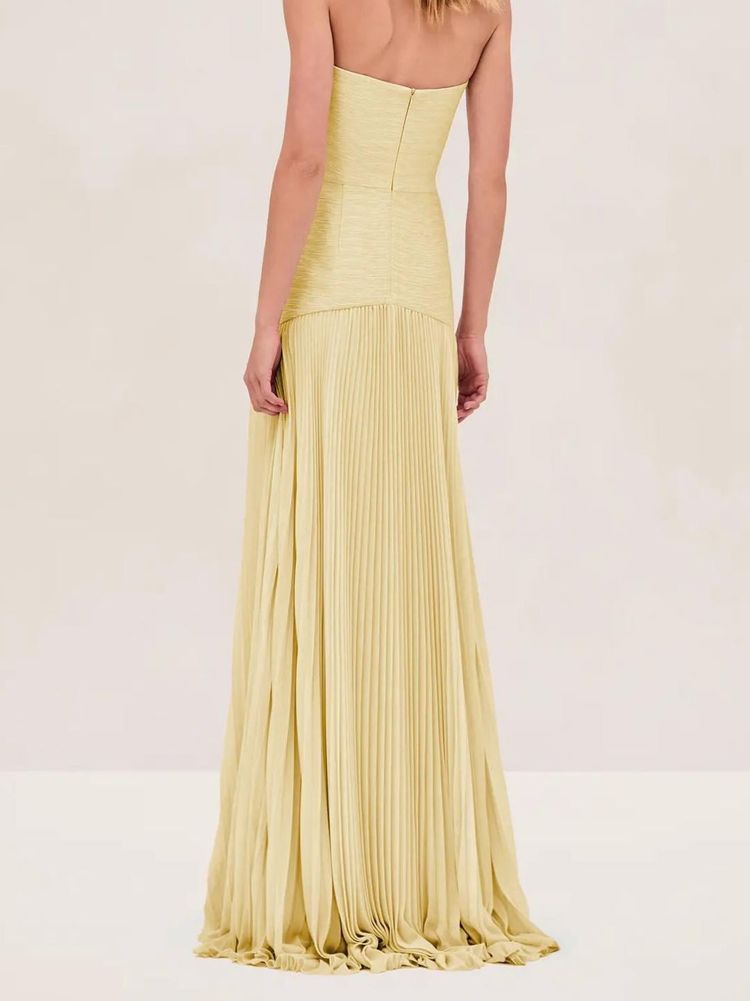 Close-up of the structured strapless bodice and dropped waist seam on the yellow pleated maxi dress