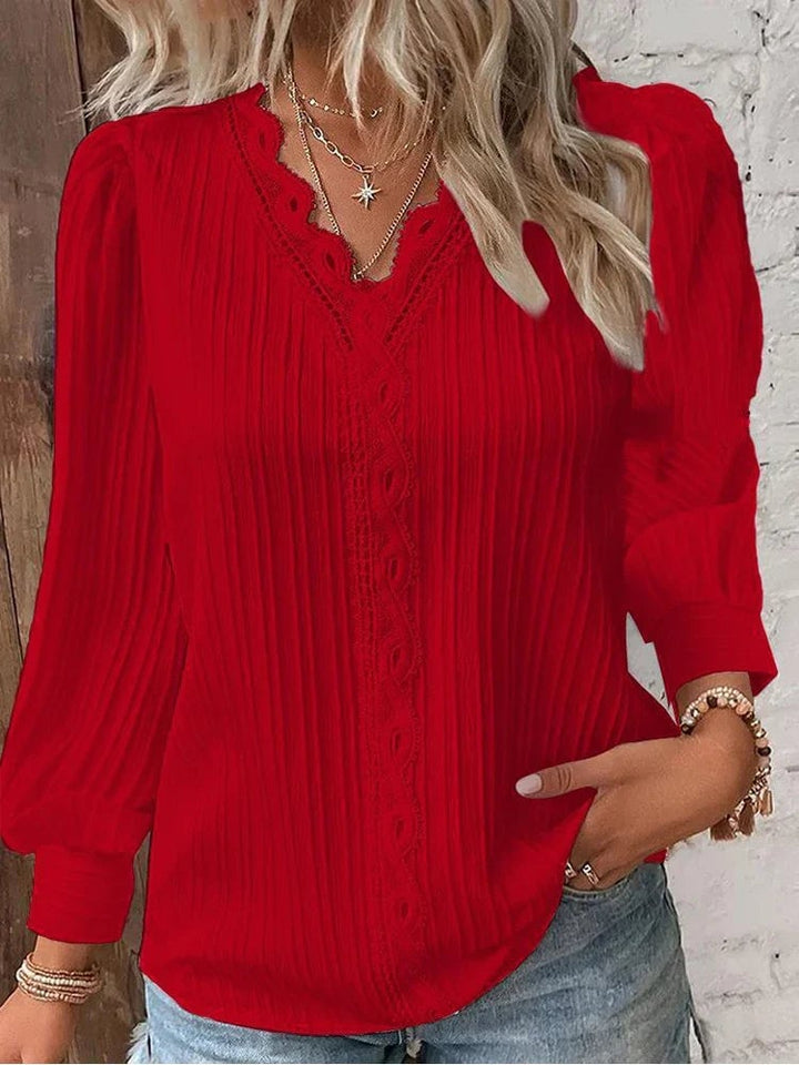 Flat lay of a light blue chiffon blouse with lace neckline detail on a neutral background
