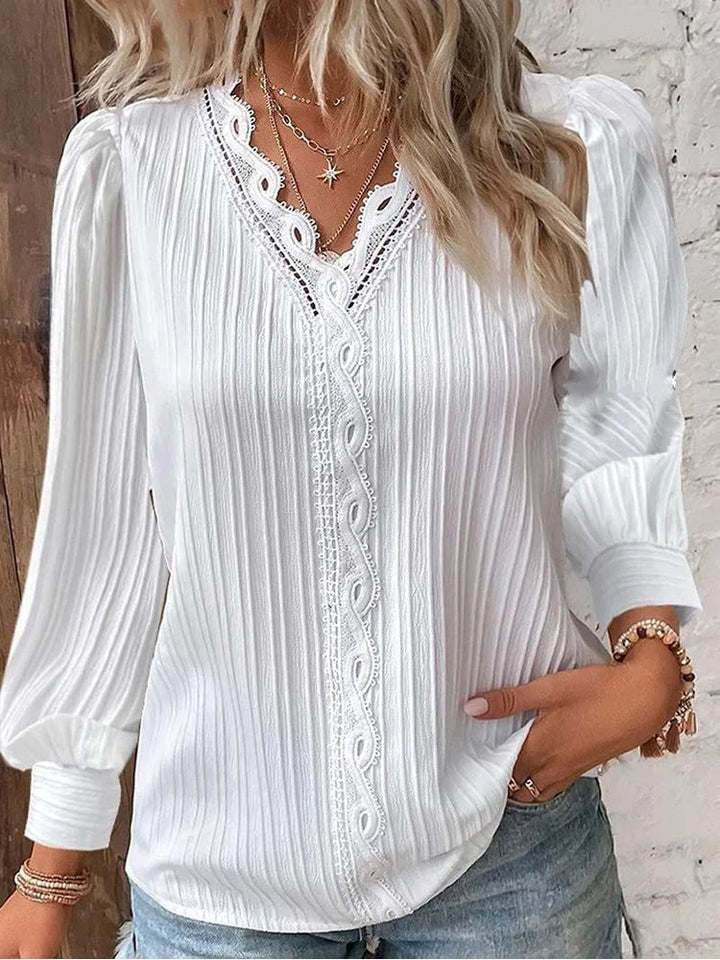 Woman wearing a black chiffon blouse with lace front detail and puff sleeves