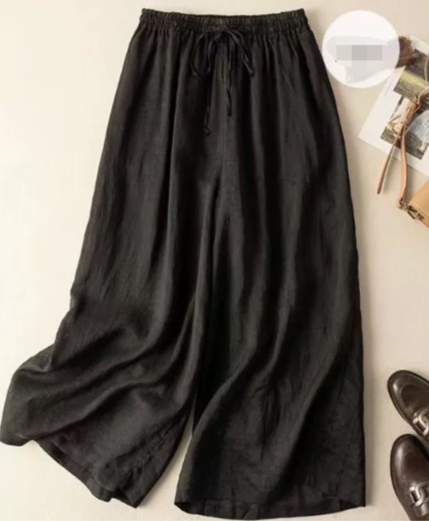 Model wearing relaxed wide-leg pants with a flowing silhouette and gathered elastic waistband in a neutral setting