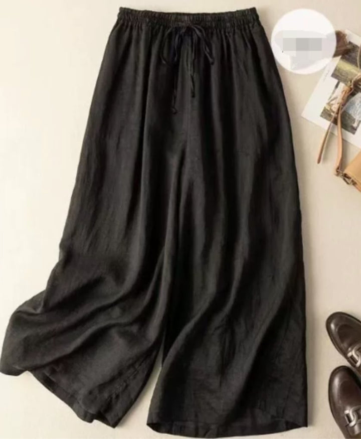 Model wearing relaxed wide-leg pants with a flowing silhouette and gathered elastic waistband in a neutral setting