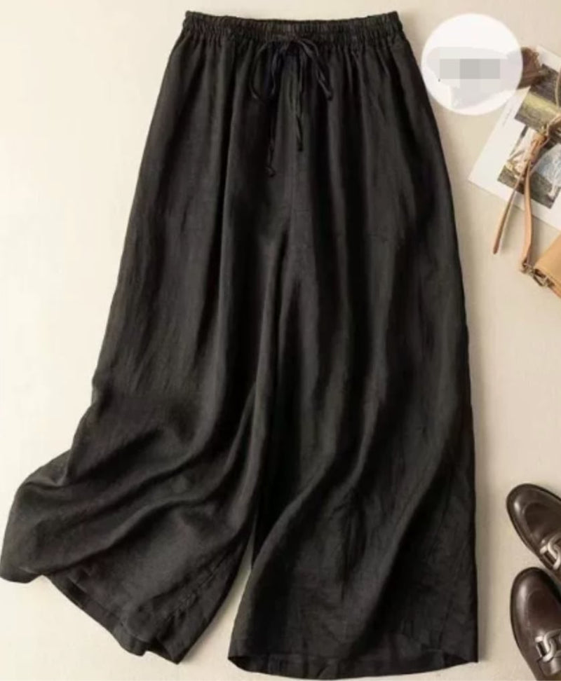 Model wearing relaxed wide-leg pants with a flowing silhouette and gathered elastic waistband in a neutral setting