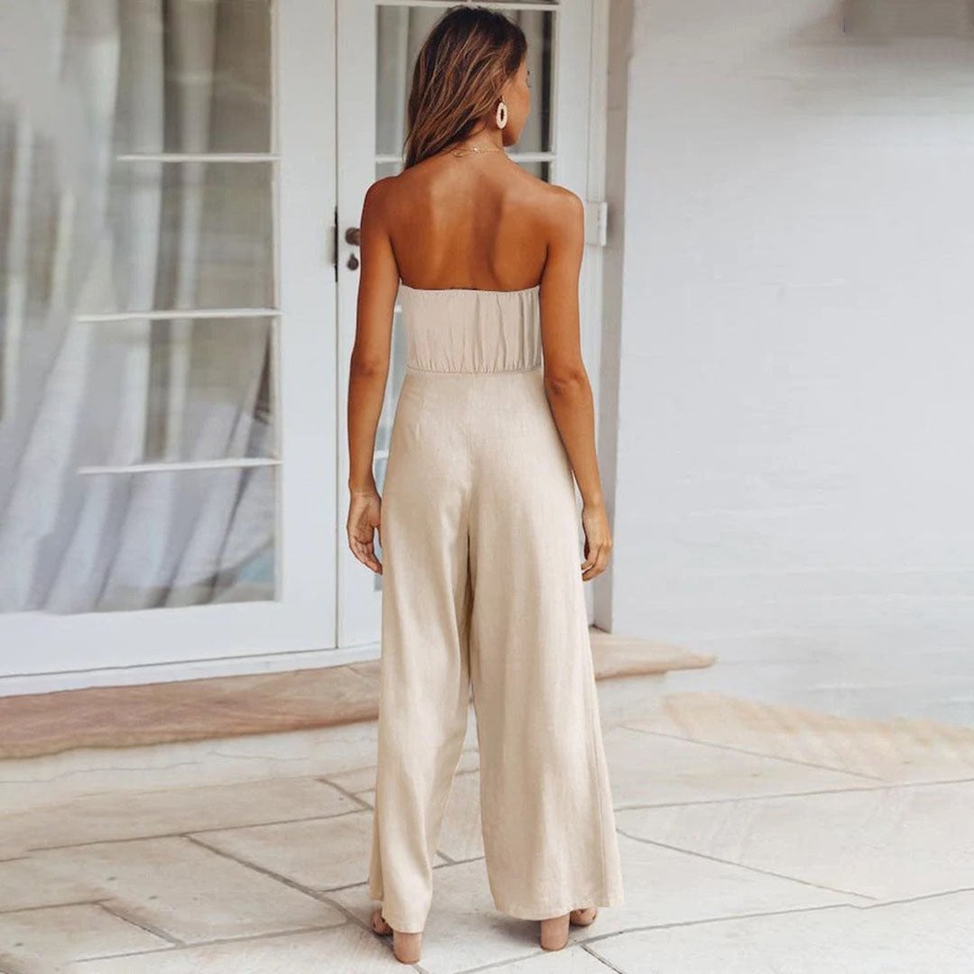 Woman wearing the Sandy jumpsuit in green styled with gold jewelry and strappy sandals