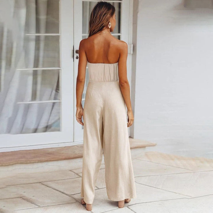 Woman wearing the Sandy jumpsuit in green styled with gold jewelry and strappy sandals