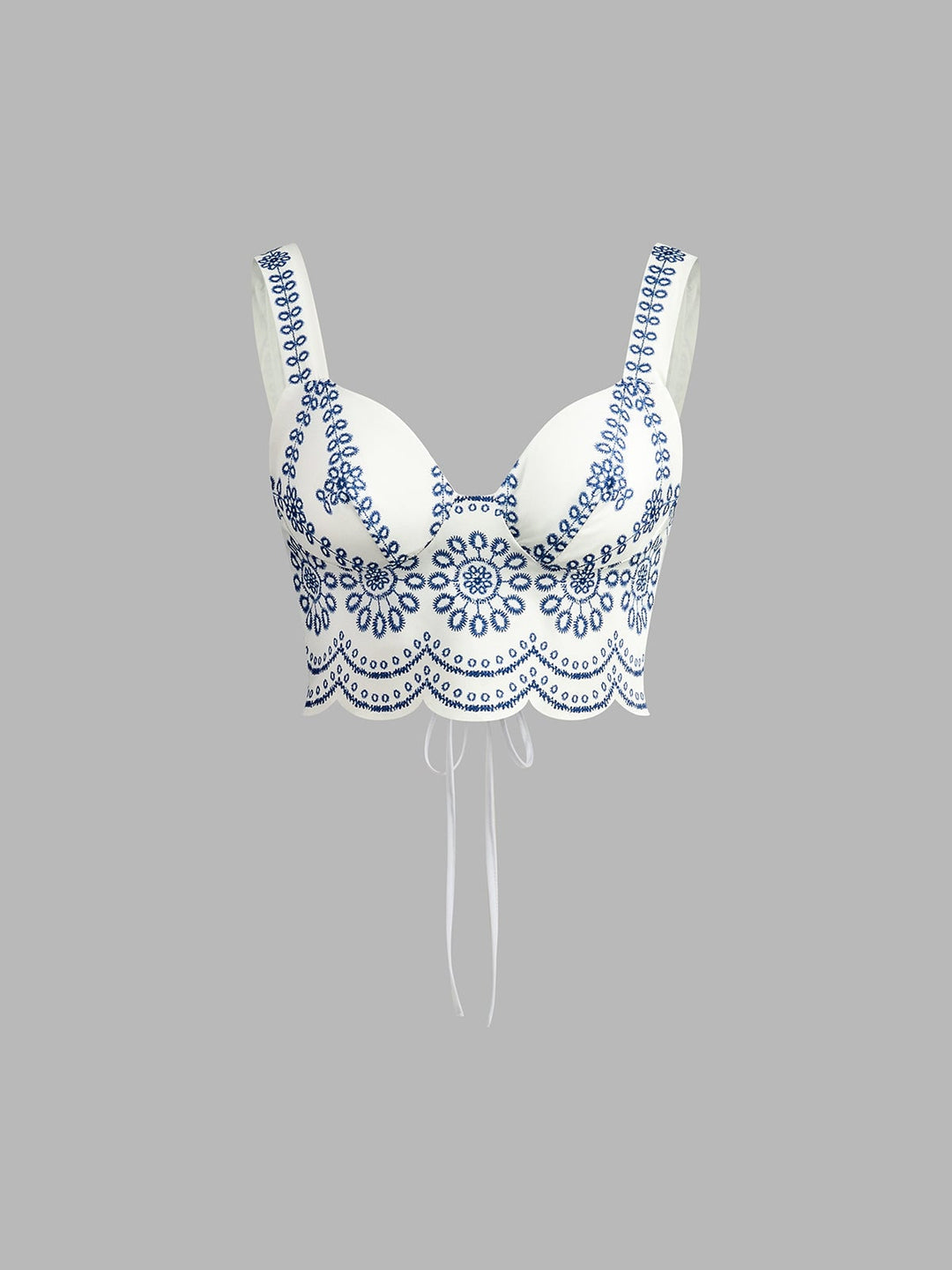 Close-up of intricate blue floral embroidery and scalloped hem on the crop top