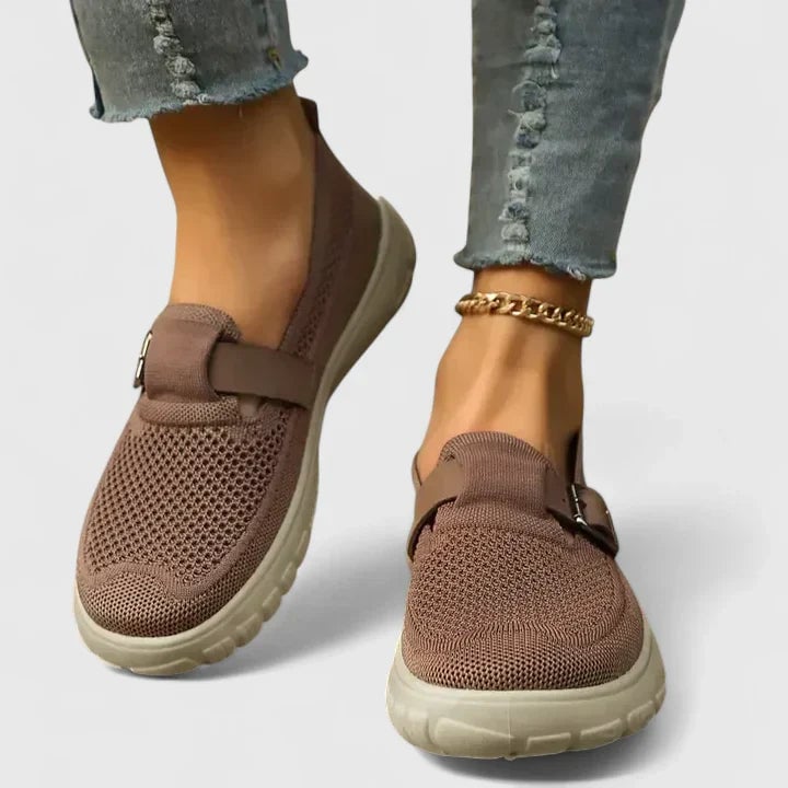 Close-up of Sara slip-on sneaker showing suede-look contrast panel and metal buckle strap detail