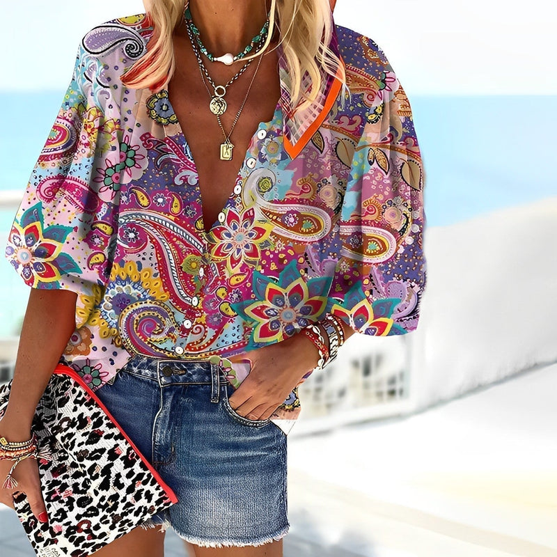 Woman wearing a relaxed-fit multicolor paisley print button-up blouse with V-neckline and 3/4 sleeves